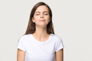 woman in a white t shirt against a neutral background breathing clean, fresh air